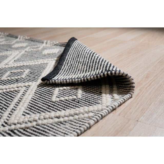Modern Kilim Black Handmade Wool Rug, Country of Origin: India. This striking flat-woven piece showcases the enduring...