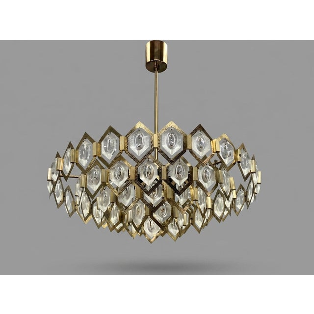 Striking 1960s chandelier with a sculptural radial form, combining faceted glass elements and a brass structure for a...