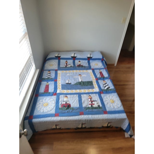 This charming handmade quilt features a vibrant nautical theme, showcasing appliquéd lighthouses, sailboats, suns, and...