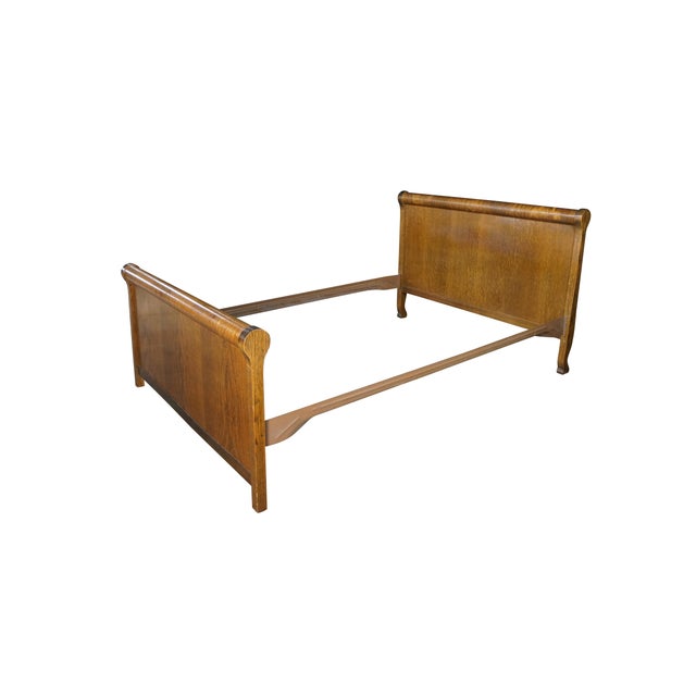 An antique Late Victorian Empire inspired sleigh bed frame. Crafted from quartersawn oak, displaying a heavily figured...