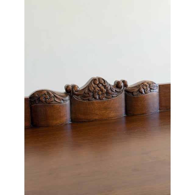 W54 D21.75 H40.75 A beautifully crafted vintage oak server featuring hand-carved floral details, sculpted acorn feet, and...