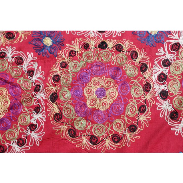 On a red cotton background, this large vintage Suzani from Samarkand, Uzbekistan, showcases 40 round medallions encircled...