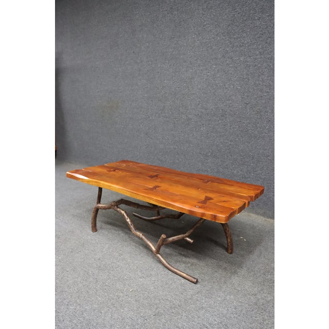 Striking mid-century organic modern coffee table featuring a live edge plank top paired with a sculptural iron branch-form...
