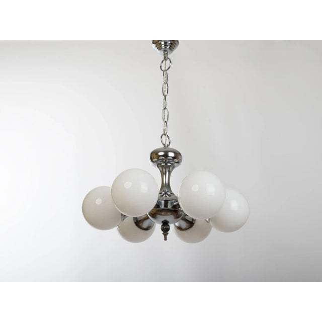 A vintage 6-light chandelier with white opal glass globes, metal nickel plated shade holders, a chain. Spain, circa 1960s....