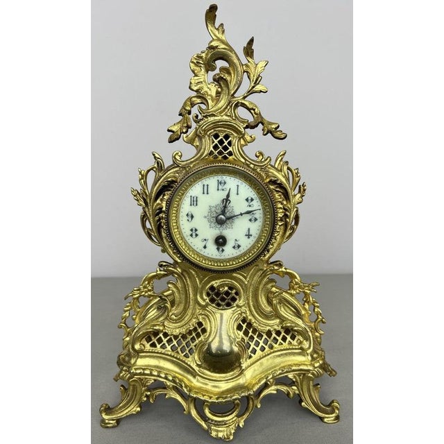 An elegant Vintage French brass clock with an elaborate decorative case, ornate scrolling forms, openwork detailing,...