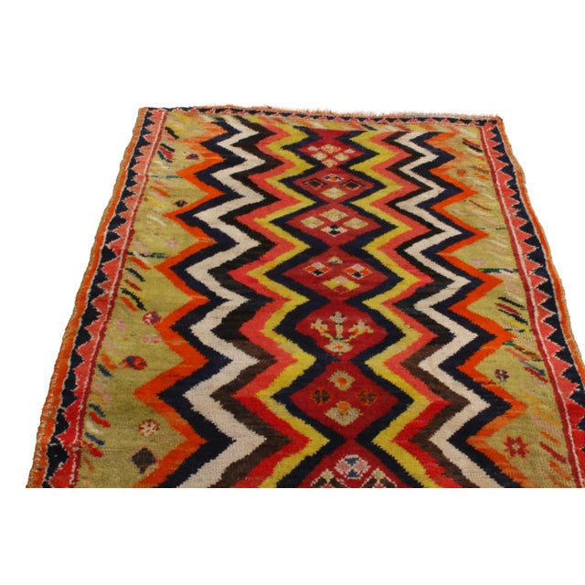 Originating from Persia between 1900-1910, this antique hand-knotted Gabbeh wool rug hosts a unique variety of unfolding...