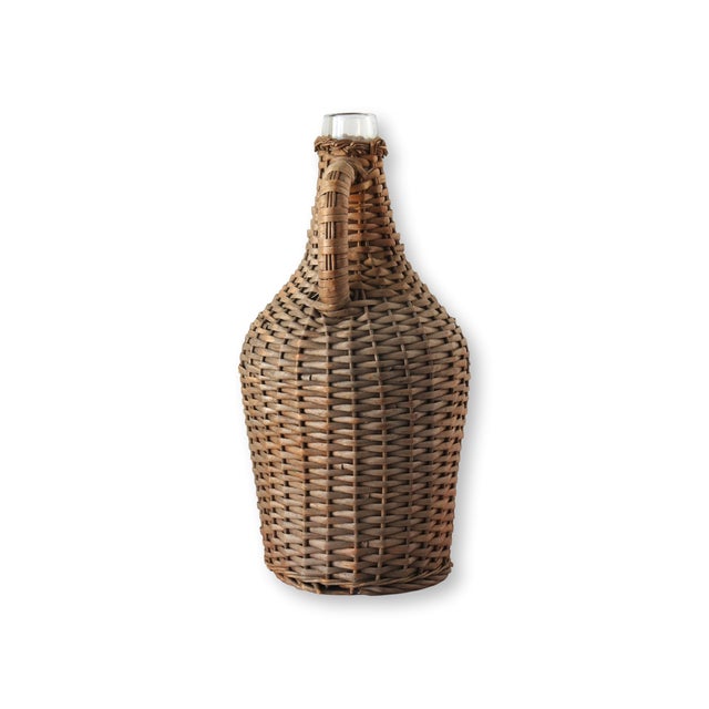 This antique French wicker-covered demijohn bottle is a rustic yet elegant piece from early 20th-century France....