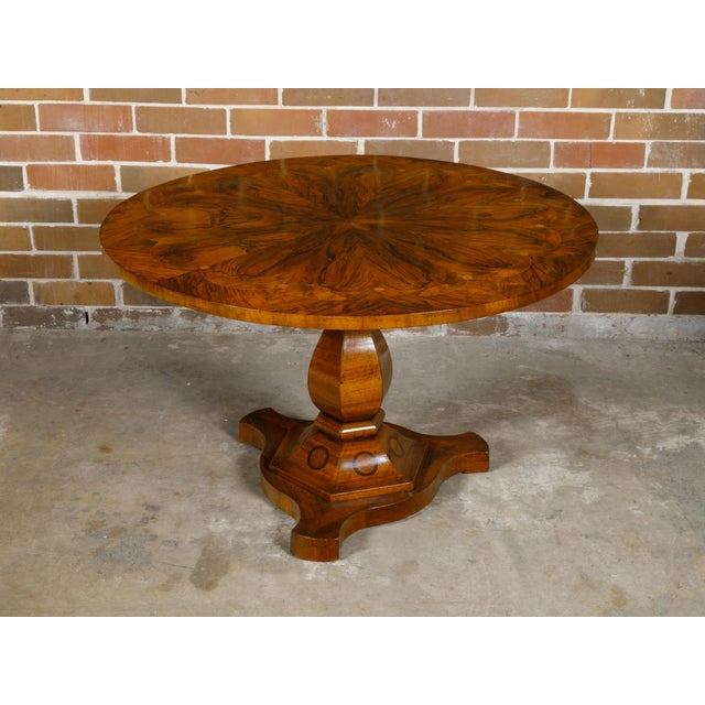 A Biedermeier period table from the 19th century with flame walnut circular top adorned with exquisite radiating motif and...