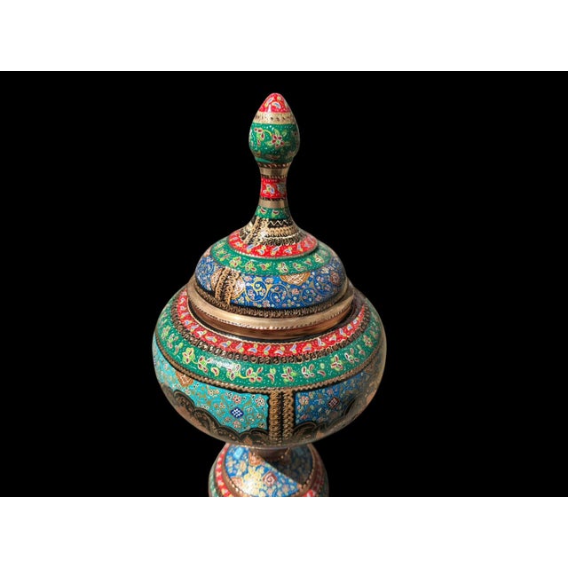 A vintage copper covered urn with a bulbous body, pedestal base, and tall finial lid, fully detailed by hand with engraved...
