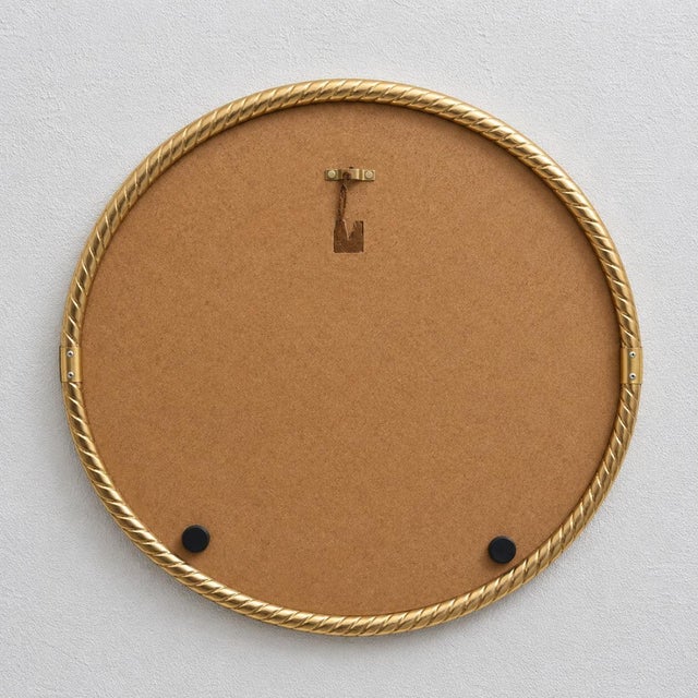 An elegant round wall mirror with a decorative, twisted frame made of brass or brass-plated metal. The piece is designed...