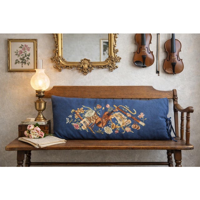 An elevated vintage needlepoint lumbar pillow featuring a refined orchestral still-life—violin, tambourine, flute, and...