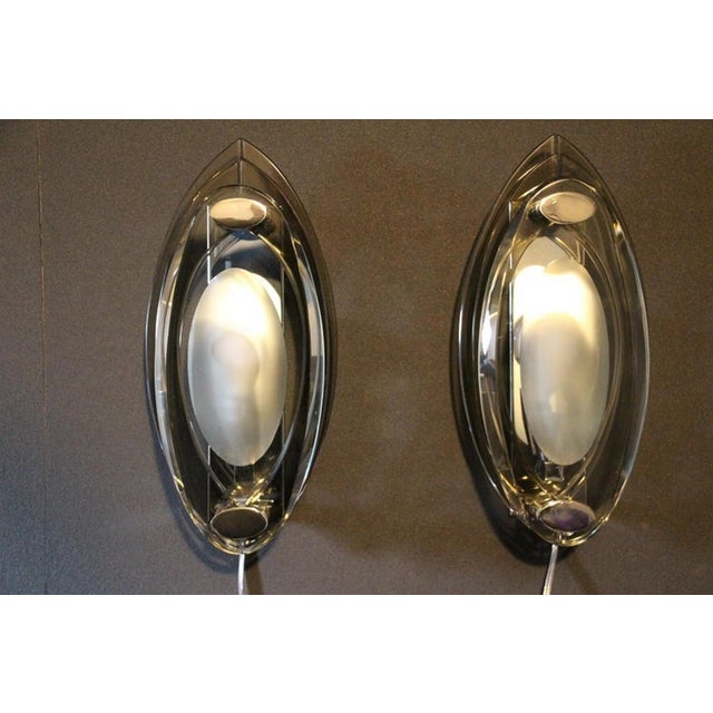 This pair of sconces in crystal glass features 3 glass panels mounted on a chromed metal base. The first piece of glass is...
