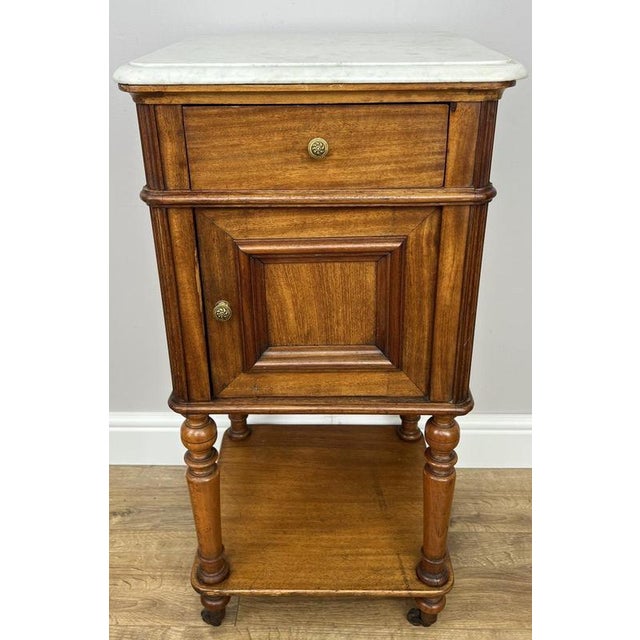 A characterful Antique French single bedside table, beautifully crafted in walnut and topped with an elegant marble...