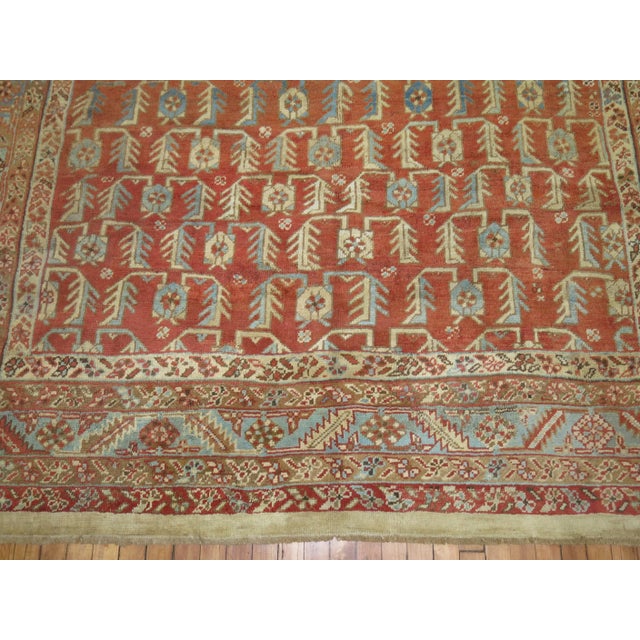 An early 20th century Persian Bakshaish Rug containing a spiraling all-over design on an orange-colored ground with...
