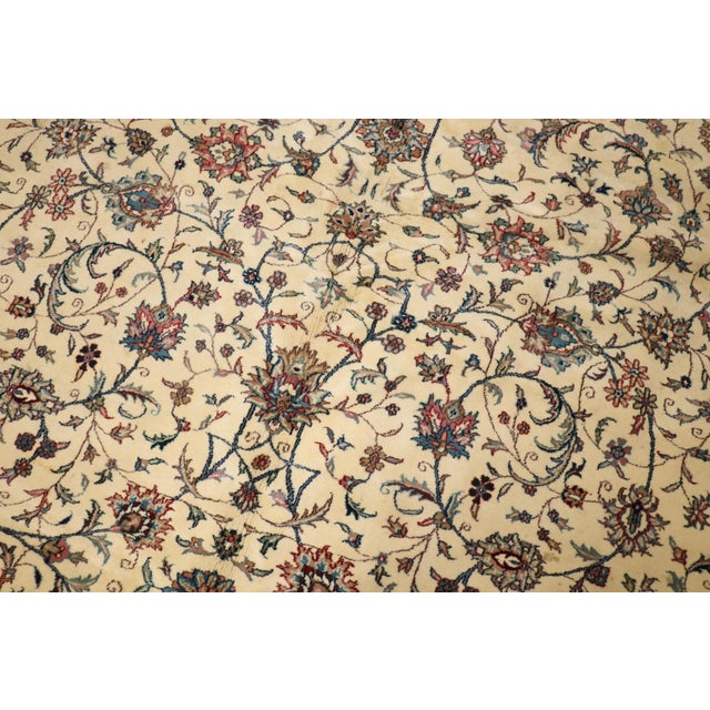 Room size Indian rug with an all over floral design on an ivory ground. Border in deep green Mesures: 10' x 13'3''