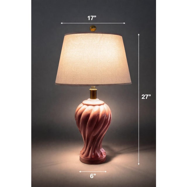 A sculptural vintage Hollywood Regency table lamp featuring a soft blush-pink glazed ceramic body with elegant spiral...