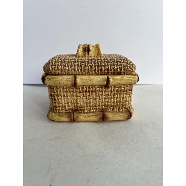 A single rectangular shaped lidded ceramic box featuring faux bamboo trim and handle with woven patterned sides. Interior...