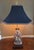 Elegant Asian figure lamp. Lovely detail in the hand painted porcelain. Brass finial and Pagoda shade by Morlee is...