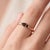A subtle, minimalist solitaire featuring an earthy smoky-brown marquise-cut quartz set in an east-west orientation, held...