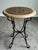 An elegant Mediterranean-inspired accent table featuring a richly detailed decorative inlaid top set above a sculptural...