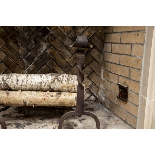 A pair of antique wrought iron andirons (fireplace log holders) with tall spiral-twist shafts with scrolled finials,...