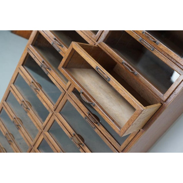 This haberdashery cabinet was produced during the 1930s in the Netherlands. It features 24 drawers in oak with glass...