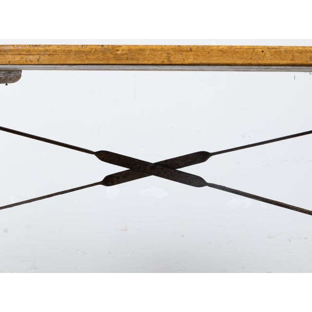 A French Turn of the Century console table circa 1900 with rectangular planked wooden top, steel base made of gracefully...