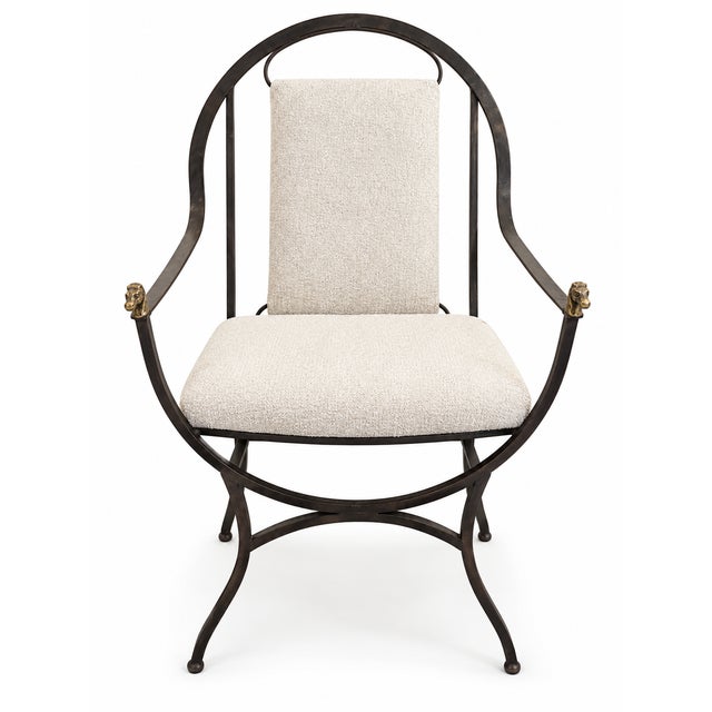 A distinctive metal armchair featuring a sculptural rounded frame with gracefully curved arms and legs. The dark iron...