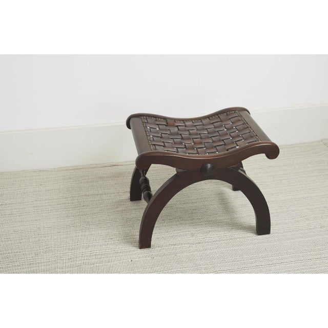 Spanish Revival vintage stool featuring a dark wood frame, hand-woven leather strap seat finished with studs. One...