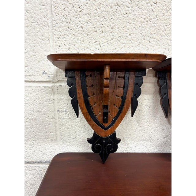 This is a charming pair of antique Arts & Crafts or Gothic Revival wall brackets featuring shield-form supports, ebonized...