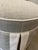 This round ottoman includes a welted and boxed cushion atop a long kick pleat skirt. Greige linen with Natural linen welt...
