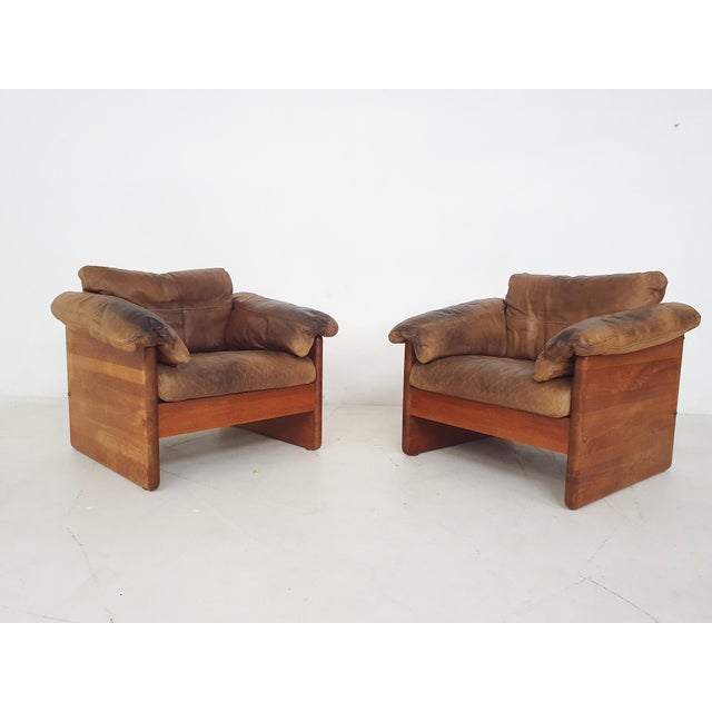 About this item Set of two teak lounge chairs and ottoman, with brown leather cushions. The leather has gained a nice...