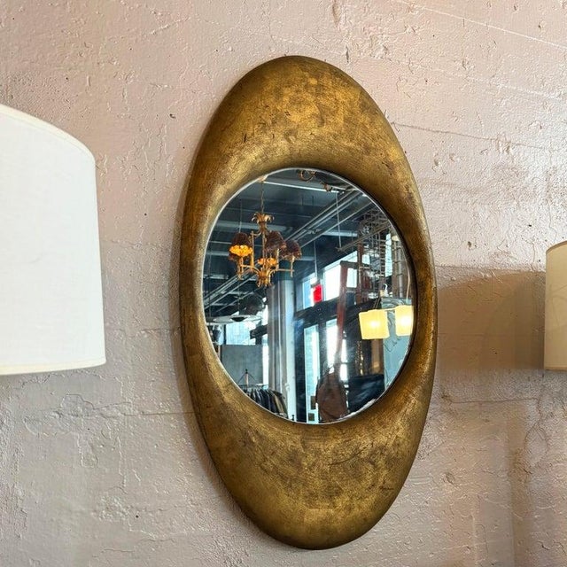 This striking oval wall mirror features an antique cast zinc metal frame with a patinated gilt finish. The frame is an...