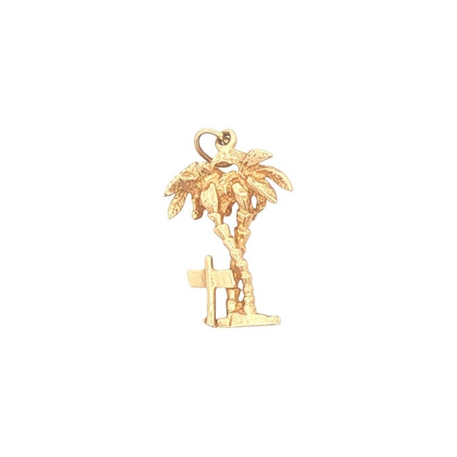 A vintage 14k gold charm featuring a detailed palm tree design. The charm includes a small sign with "Florida" inscribed....