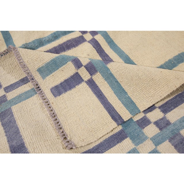 Beautiful Modern Hand-woven Kilim Handmade Wool Rug with a geometric design on an ivory field with blue accents. This rug...