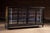 Large antique wood-framed general store display case with a black-painted finish and slanted glass front. The floor-...