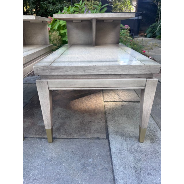 A matched pair of mid-century step end tables by Lane Furniture of Altavista, Virginia. Their pale, bleached, glossy...