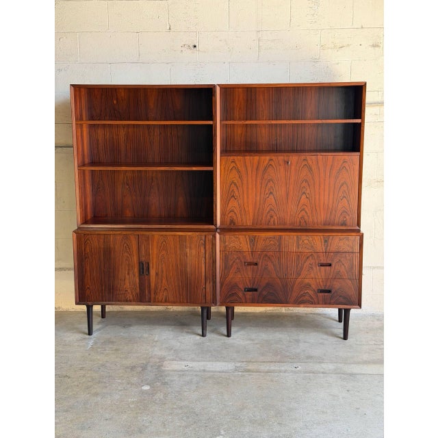 This impressive modular modular storage system presents a dual-bay layout combining open bookcases over functional base...