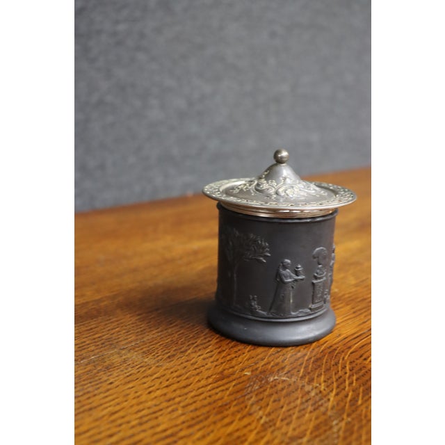 Wedgwood Black Basalt covered jar with molded Neoclassical relief decoration depicting classical figures, trees, and...