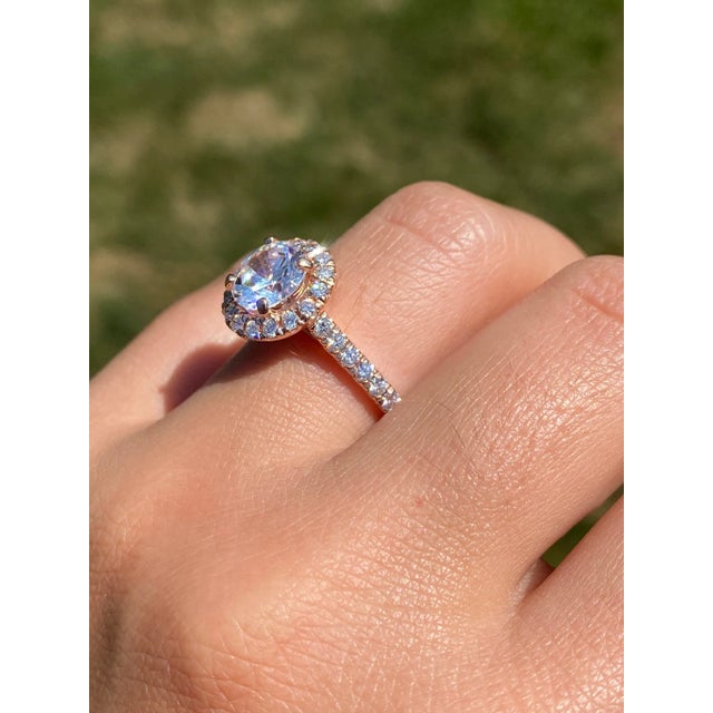 The Argyle: Rose Gold Halo Engagement Ring. The ring has a cubic zirconia center and is surrounded by round brilliant cut...