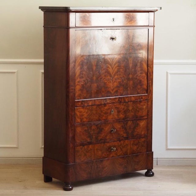 A louis-philippe style secretary desk, made around 1850, with flamed mahogany veneer and a marble top. The structure is...