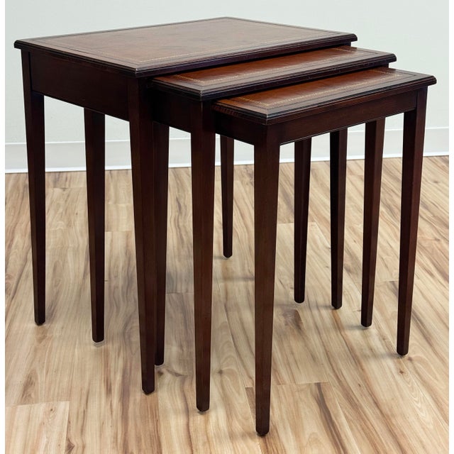 Set of three vintage leather top mahogany nesting tables manufactured by Heritage-Henredon. Tables each feature leather...