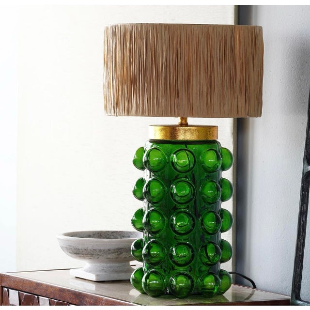 The retro Bubbles Table Lamp has a green glass base with rows of large, circular bulbs to give it a grand style. The tall,...