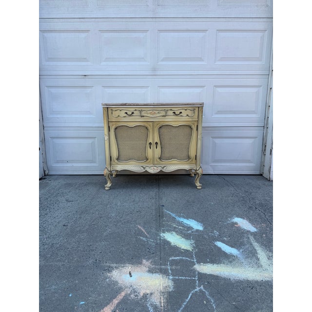 We have an absolutely beautiful vintage French Provincial marble top cabinet with cane doors for sale. This beautiful...