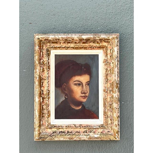 This vintage oil portrait is an intimate, softly lit study of a young woman, shown in three-quarter profile with her gaze...
