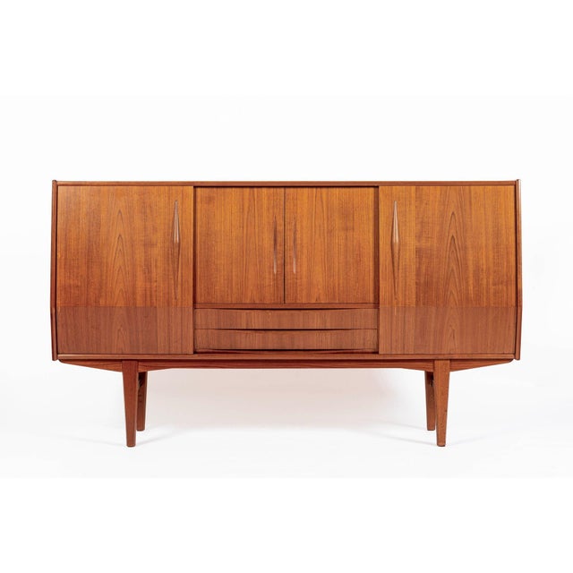 This vintage mid-century Danish modern teak high sideboard or bar cabinet attributed to E.W. Bach was produced in Denmark...