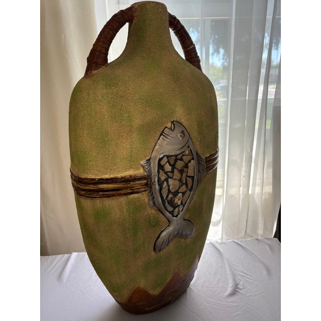 This vase showcases a prominent fish motif with an inlaid mosaic or textured relief scale pattern. It is made during the...