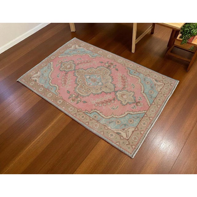 This is a beautiful vintage hand knotted distressed finish rug from Turkey. It has primary colors on petite orchid field....