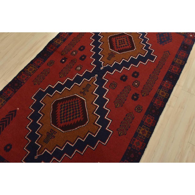 An authentic vintage tribal Baloch rug hand-knotted with fine wool and natural dyes. This rug features geometric...