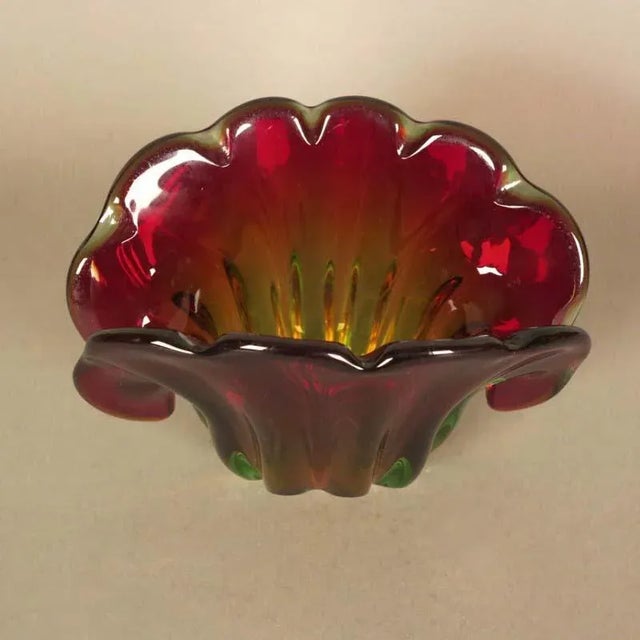 This red and green Murano glass bowl has a wavy edge in the shape of a shell. The shell can sit vertically or at 45...